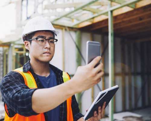 Construction Worker Looking at Mobile Device in the Field