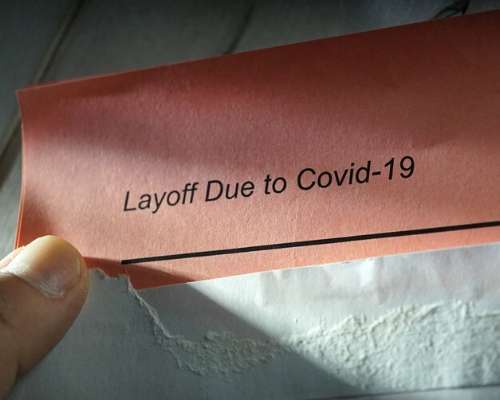 Holding a paper that reads 'Layoff Due to COVID-19'