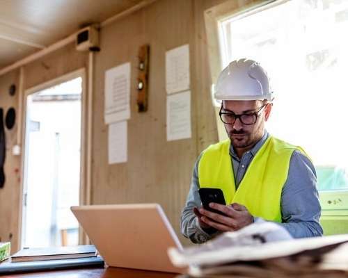 Construction worker on site using mobile device.