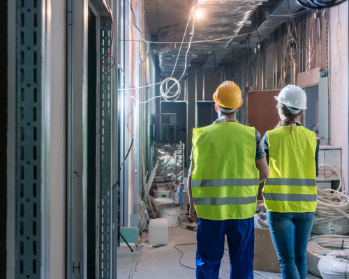 Two construction workers assessing electrical fittings