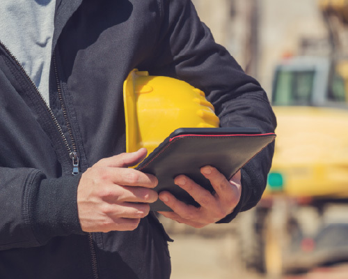 Man holding hard hat and ipad