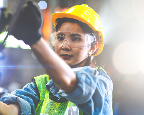 Woman in hard hat working on a machine.