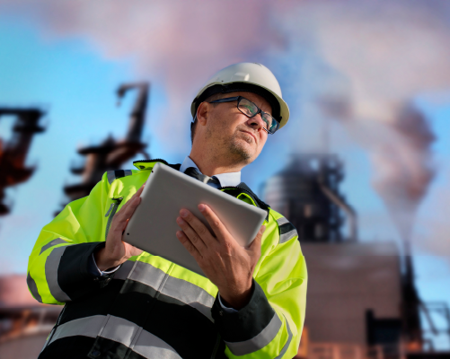 Construction manager standing with a tablet with construction site in the background.